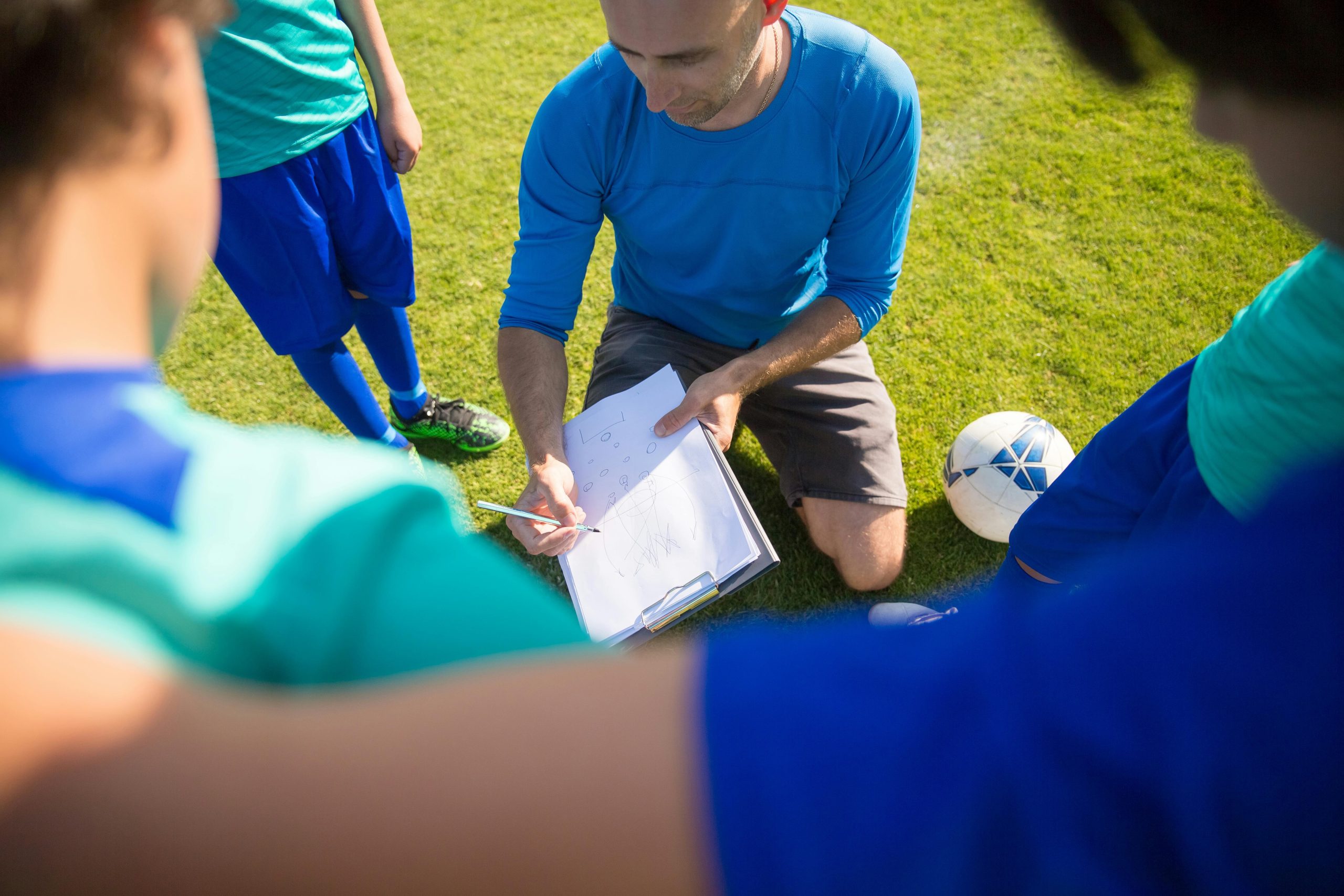 A green parrot interacting with a small silver bell during a training session.